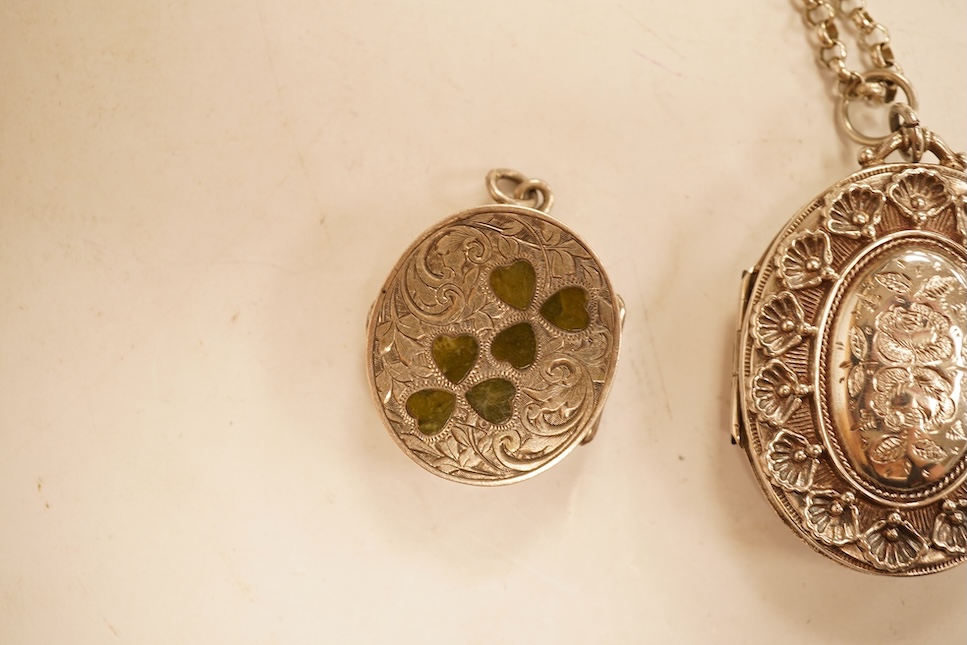 A late Victorian embossed and engraved oval silver locket, 42mm, on a later white meta belcher link chain, together with an Edwardian silver and hardstone inlaid pill box, now with pendant mount.